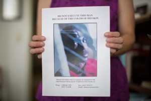 Clemency flyer for Robert Bacon, created by the Center for Death Penalty Litigation, held by Robert's attorney, Gretchen Engel. The flyer, which includes a photograph of Robert, has a title in all caps that reads: DO NOT EXECUTE THIS MAN BECAUSE OF THE COLOR OF HIS SKIN